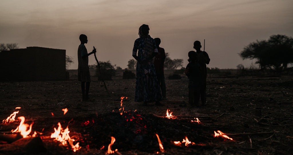 Men stand around a fire that burns at sunset in Chad, Africa | Join neverthirst in serving the unreached in Africa